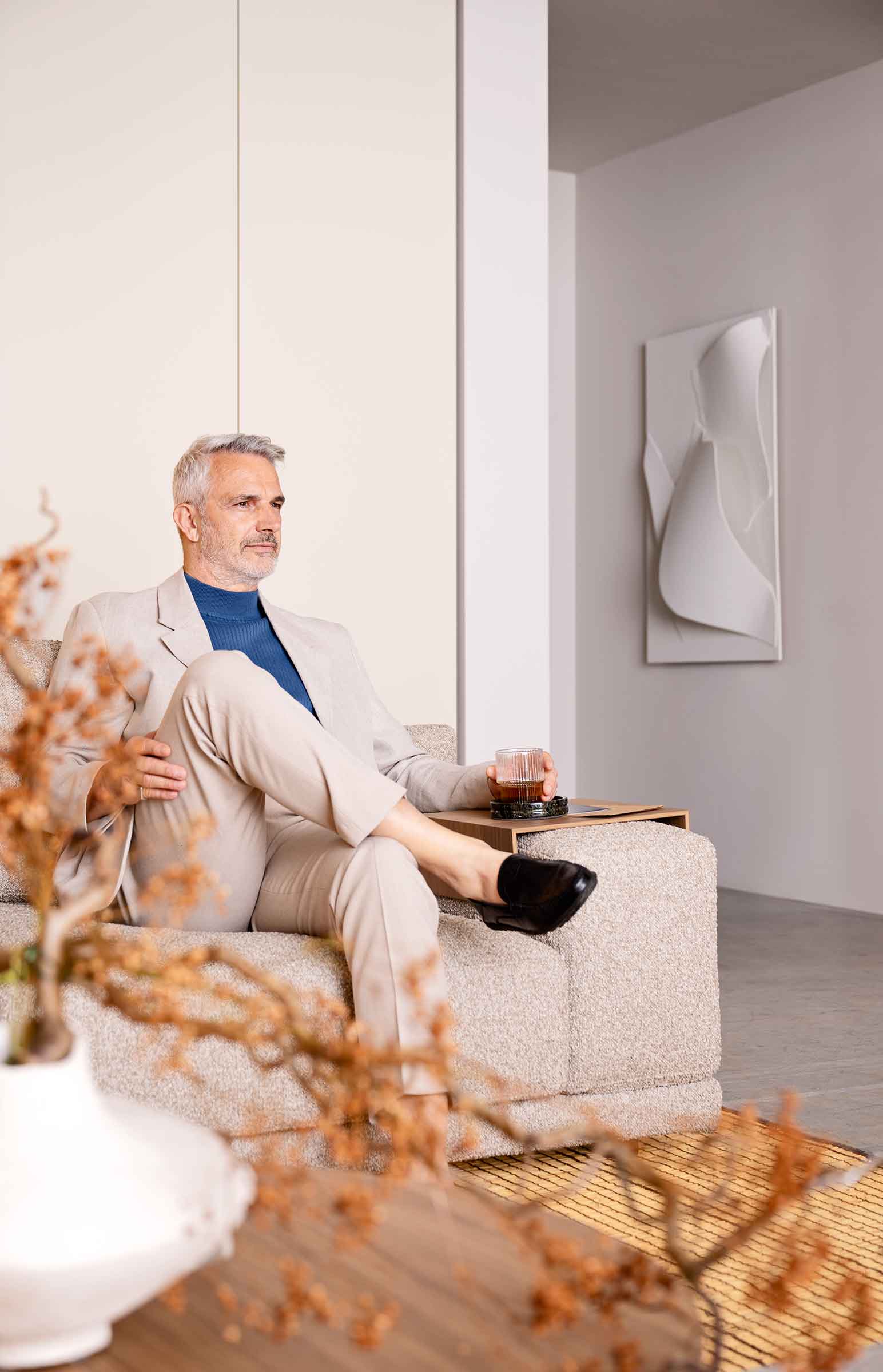 Smėlio bouclé sofa Mac su sėdinčiu žmogumi, portretinis kadras, Novamobili